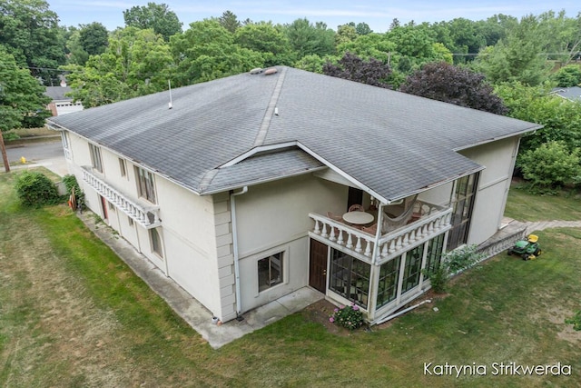 1217 El Camino Dr NW, Grand Rapids, MI 49504 - rear view of house featuring stucco siding, a shingled roof, a lawn, and a wooded view