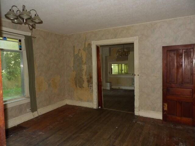 209 E High St, Union City, MI 49094 - unfurnished room with a chandelier and dark wood-style floors