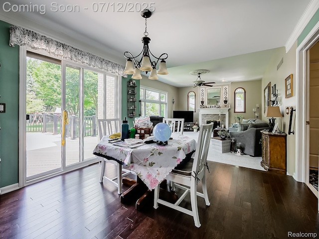 12495 Howland Park Dr, Plymouth, MI 48170 - dining space with dark wood-style floors, a chandelier, ceiling fan, and a fireplace