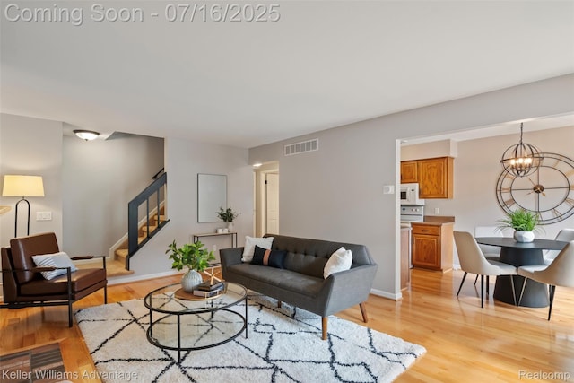 7741 Lake Ridge Dr, Commerce Twp, MI 48327 - living area featuring stairs, light wood-style floors, and a chandelier