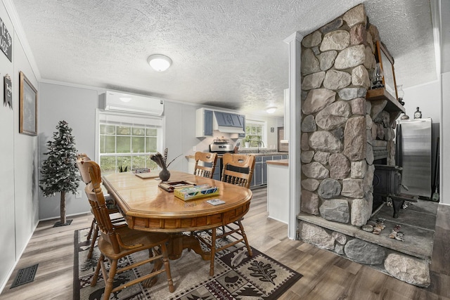 797 Beaver Rd, Bitely, MI 49309 - dining space with a wall mounted AC, a textured ceiling, light wood-style flooring, and ornamental molding