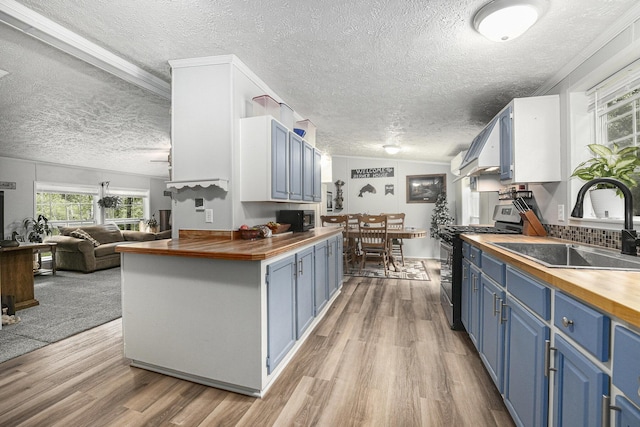 797 Beaver Rd, Bitely, MI 49309 - kitchen with wooden counters, stainless steel gas range oven, blue cabinetry, a textured ceiling, and light wood-style floors