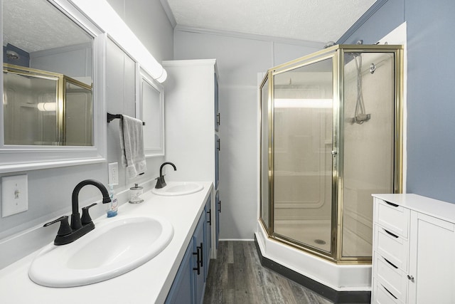 797 Beaver Rd, Bitely, MI 49309 - full bathroom featuring a textured ceiling, a shower stall, wood finished floors, double vanity, and ornamental molding
