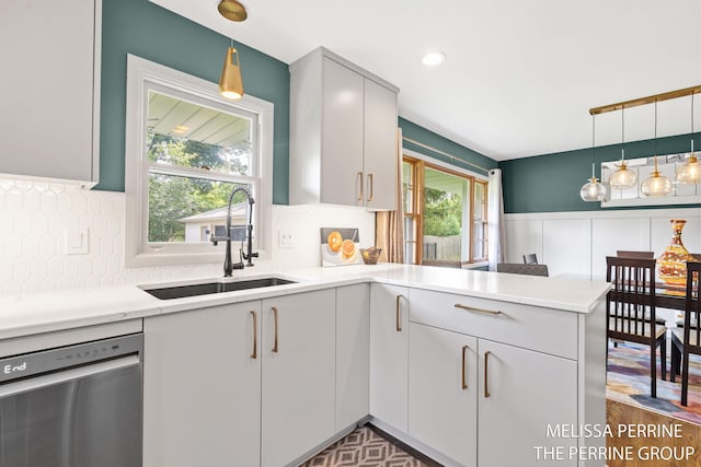 116 Loch Lomond Ave NE, Grand Rapids, MI 49546 - kitchen with dishwasher, a peninsula, light countertops, backsplash, and hanging light fixtures
