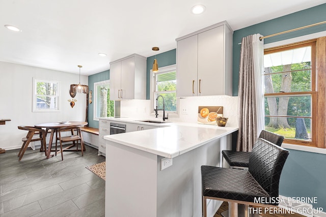116 Loch Lomond Ave NE, Grand Rapids, MI 49546 - kitchen featuring light countertops, hanging light fixtures, a peninsula, tasteful backsplash, and recessed lighting