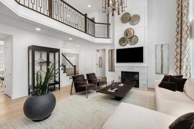 3909 Sandpiper Dr, Troy, MI 48083 - living room featuring wood finished floors, stairs, a tile fireplace, a towering ceiling, and a chandelier