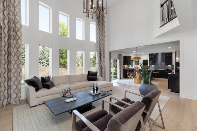 3909 Sandpiper Dr, Troy, MI 48083 - living area featuring a towering ceiling, a chandelier, light wood-style floors, and healthy amount of natural light