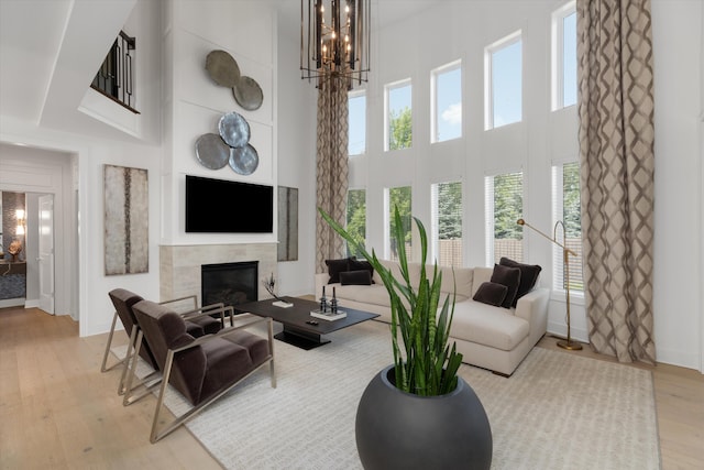 3909 Sandpiper Dr, Troy, MI 48083 - living room featuring a high ceiling, light wood-style floors, a tile fireplace, and a chandelier