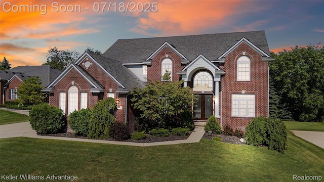 25506 Stanley Ln, South Lyon, MI 48178 - traditional-style house with brick siding, a lawn, a shingled roof, and french doors