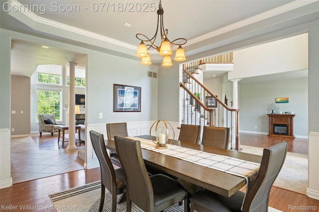 25506 Stanley Ln, South Lyon, MI 48178 - dining area with ornate columns, a glass covered fireplace, stairway, a tray ceiling, and ornamental molding