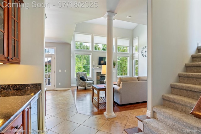 25506 Stanley Ln, South Lyon, MI 48178 - living room with ornate columns, stairs, light tile patterned floors, and a fireplace