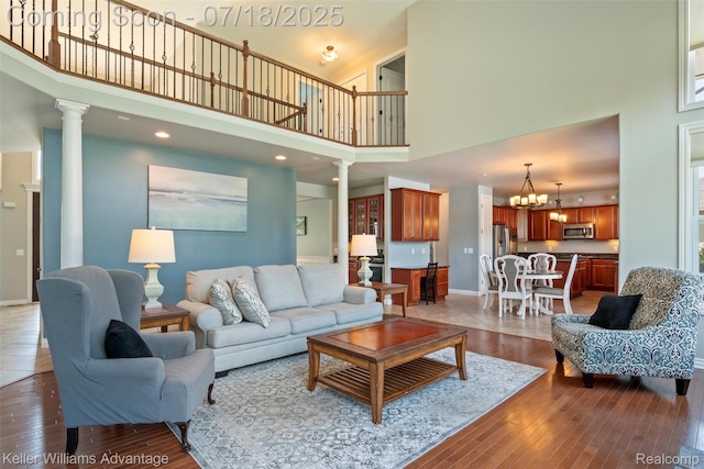 25506 Stanley Ln, South Lyon, MI 48178 - living room with a high ceiling, ornate columns, a chandelier, dark wood-style floors, and recessed lighting