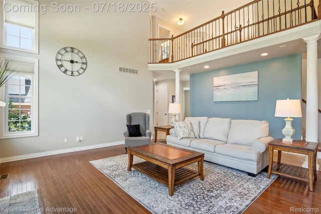 25506 Stanley Ln, South Lyon, MI 48178 - living room featuring ornate columns, a high ceiling, and wood-type flooring