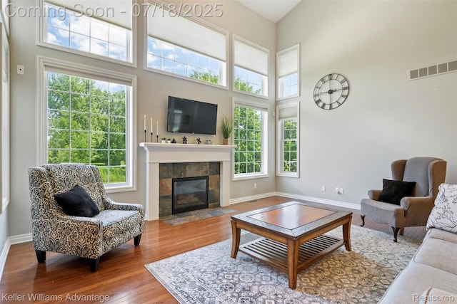 25506 Stanley Ln, South Lyon, MI 48178 - living room featuring wood finished floors, healthy amount of natural light, a tile fireplace, and a high ceiling