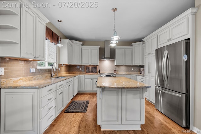 9589 Wellington Ct, Clarkston, MI 48348 - kitchen with freestanding refrigerator, wall chimney exhaust hood, a center island, light wood-style flooring, and white cabinetry