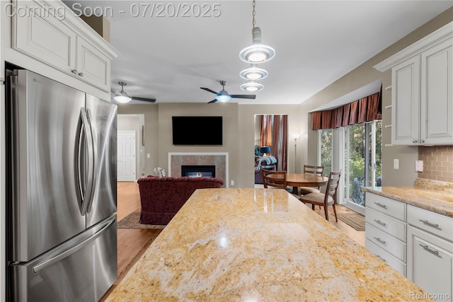 9589 Wellington Ct, Clarkston, MI 48348 - kitchen with freestanding refrigerator, ceiling fan, a glass covered fireplace, and white cabinets