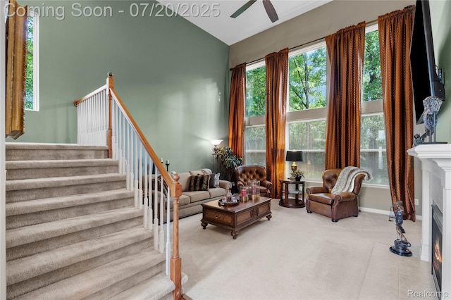 9589 Wellington Ct, Clarkston, MI 48348 - living room featuring a fireplace with flush hearth, stairway, a ceiling fan, carpet floors, and high vaulted ceiling