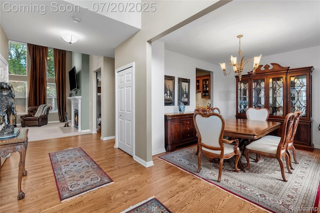9589 Wellington Ct, Clarkston, MI 48348 - dining area featuring a chandelier, wood finished floors, and a warm lit fireplace