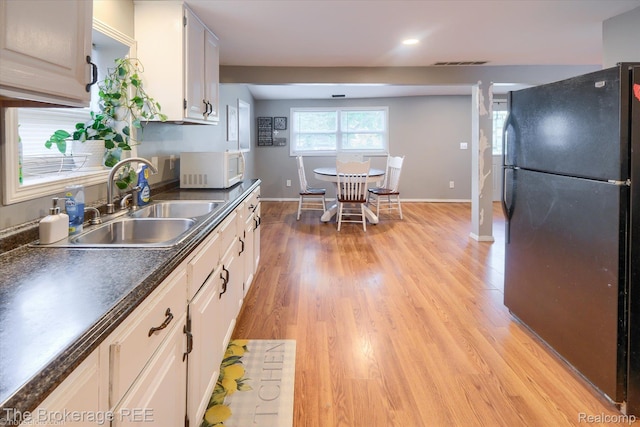 166 Indian Trl, Columbiaville, MI 48421 - kitchen featuring freestanding refrigerator, white microwave, dark countertops, light wood finished floors, and white cabinets
