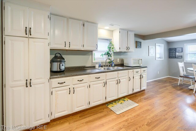 166 Indian Trl, Columbiaville, MI 48421 - kitchen with white microwave, dark countertops, white cabinetry, and light wood-style flooring