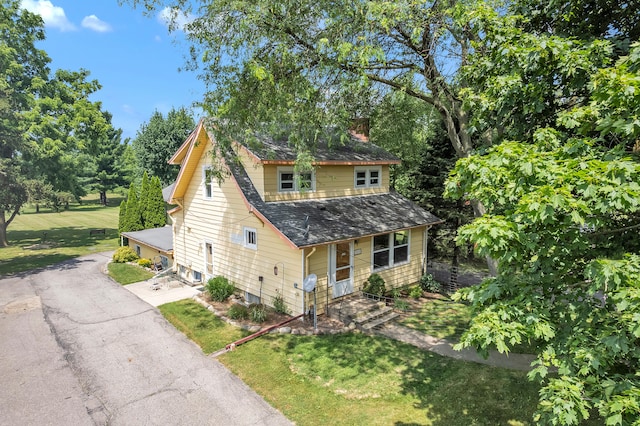 2050 S Wagner Rd, Ann Arbor, MI 48103 - view of front of home featuring a chimney, a shingled roof, a front lawn, and view of wooded area