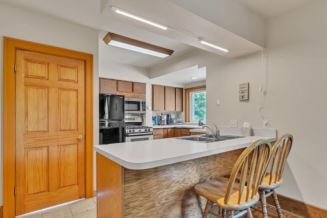 2050 S Wagner Rd, Ann Arbor, MI 48103 - kitchen featuring stainless steel appliances, a peninsula, brown cabinets, light countertops, and a breakfast bar area