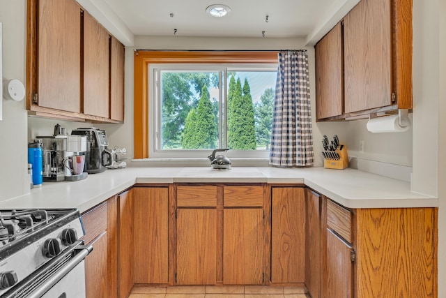 2050 S Wagner Rd, Ann Arbor, MI 48103 - kitchen with light countertops, brown cabinetry, stainless steel gas stove, and light tile patterned floors