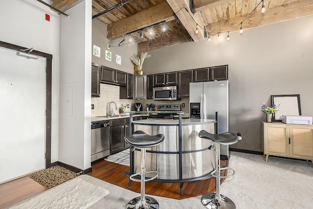 940 Monroe Ave NW Unit 416, Grand Rapids, MI 49503 - kitchen featuring stainless steel appliances, a high ceiling, a wood ceiling with exposed beams, light countertops, and track lighting