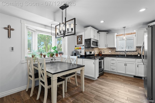 1450 N Stephen Ave, Clawson, MI 48017 - kitchen featuring stainless steel appliances, dark countertops, a chandelier, decorative backsplash, and white cabinetry