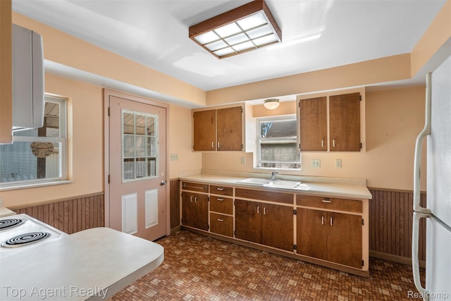 23123 E 13 Mile Rd, Saint Clair Shores, MI 48082 - kitchen featuring wainscoting, freestanding refrigerator, light countertops, brown cabinets, and wooden walls