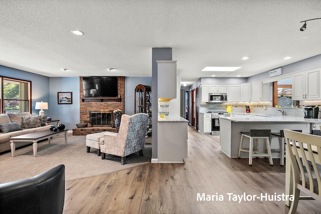 16205 Suffolk Dr, Spring Lake, MI 49456 - living area featuring a textured ceiling, a brick fireplace, light wood-style floors, and recessed lighting