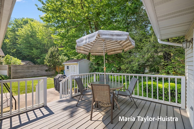 16205 Suffolk Dr, Spring Lake, MI 49456 - wooden deck with outdoor dining area, a storage unit, and a grill