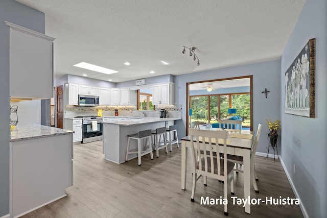 16205 Suffolk Dr, Spring Lake, MI 49456 - dining area with a textured ceiling, light wood finished floors, recessed lighting, a skylight, and a ceiling fan