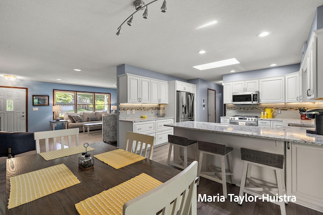 16205 Suffolk Dr, Spring Lake, MI 49456 - dining room featuring a skylight, recessed lighting, wood finished floors, and a textured ceiling