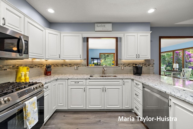 16205 Suffolk Dr, Spring Lake, MI 49456 - kitchen with appliances with stainless steel finishes, white cabinets, backsplash, wood finished floors, and healthy amount of natural light