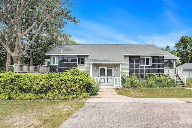 258 Division St, Eastlake, MI 49626 - view of front facade featuring roof with shingles, a front lawn, a sunroom, and a deck