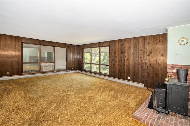 258 Division St, Eastlake, MI 49626 - unfurnished living room featuring a wood stove, wood walls, baseboard heating, and carpet flooring