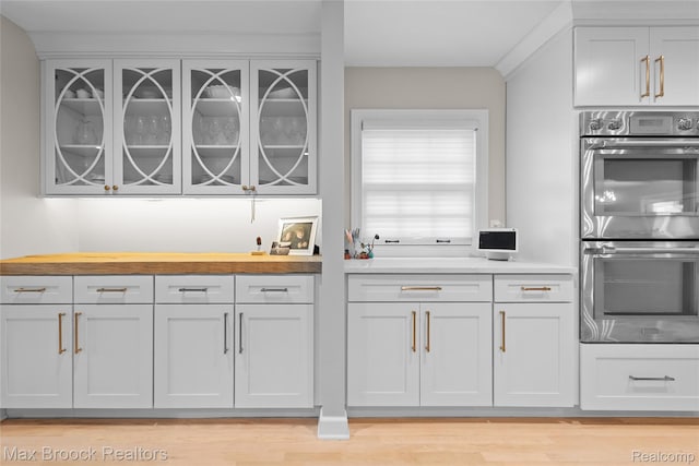 639 N Glenhurst Dr, Birmingham, MI 48009 - kitchen featuring stainless steel double oven, glass insert cabinets, butcher block countertops, and light wood-style floors