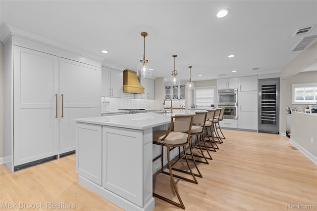 639 N Glenhurst Dr, Birmingham, MI 48009 - kitchen featuring wine cooler, stainless steel appliances, a kitchen island with sink, light wood-style floors, and recessed lighting