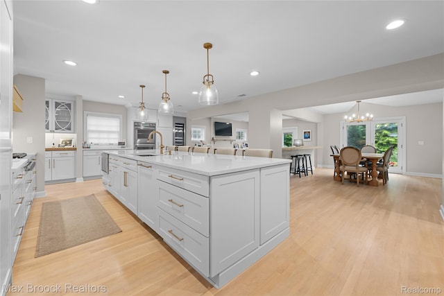 639 N Glenhurst Dr, Birmingham, MI 48009 - kitchen with a chandelier, white cabinets, light wood finished floors, recessed lighting, and a center island with sink