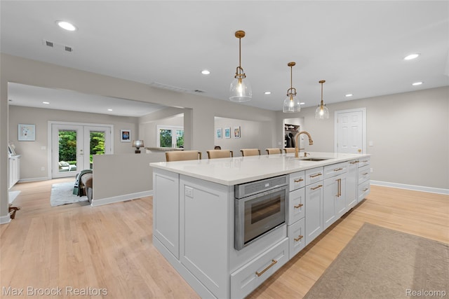 639 N Glenhurst Dr, Birmingham, MI 48009 - kitchen featuring a kitchen island with sink, light wood finished floors, recessed lighting, french doors, and decorative light fixtures