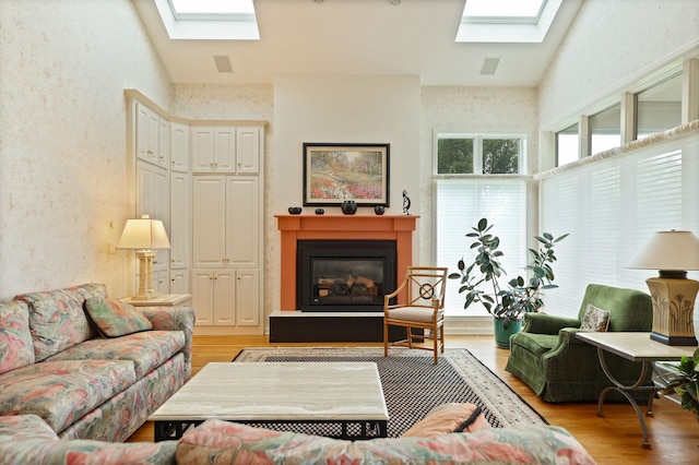 5 Mission Rdg, Frankenmuth, MI 48734 - living area featuring a skylight, light wood-style flooring, a glass covered fireplace, and a textured wall