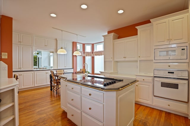 5 Mission Rdg, Frankenmuth, MI 48734 - kitchen featuring white appliances, a center island with sink, white cabinetry, light wood-style flooring, and recessed lighting