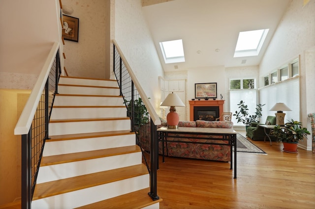 5 Mission Rdg, Frankenmuth, MI 48734 - staircase featuring a skylight, high vaulted ceiling, wood finished floors, and a glass covered fireplace