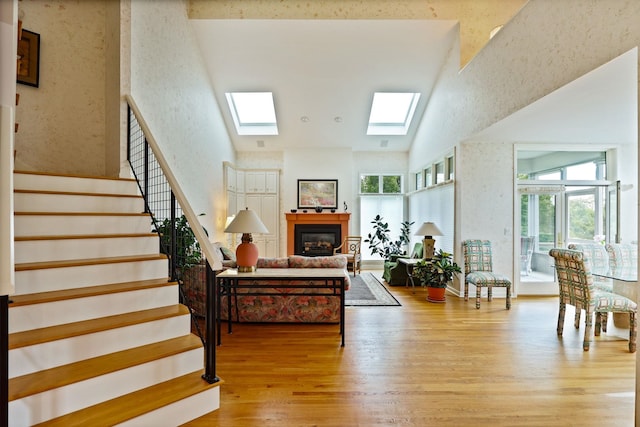 5 Mission Rdg, Frankenmuth, MI 48734 - living area featuring high vaulted ceiling, light wood finished floors, a glass covered fireplace, stairway, and a skylight