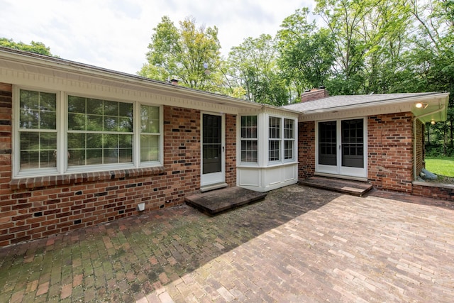 144 Barton N Dr, Ann Arbor, MI 48105 - view of front facade featuring a patio area, brick siding, a chimney, and french doors