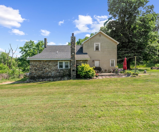 278 E Southern Rd, Coldwater, MI 49036 - rear view of property featuring a patio area, a lawn, a chimney, and stone siding