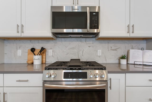 1519 Eagle Shore Ct, Hudsonville, MI 49426 - kitchen featuring stainless steel appliances, dark countertops, white cabinetry, and decorative backsplash