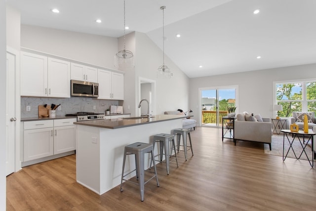 1519 Eagle Shore Ct, Hudsonville, MI 49426 - kitchen with stainless steel microwave, dark countertops, an island with sink, open floor plan, and a kitchen bar