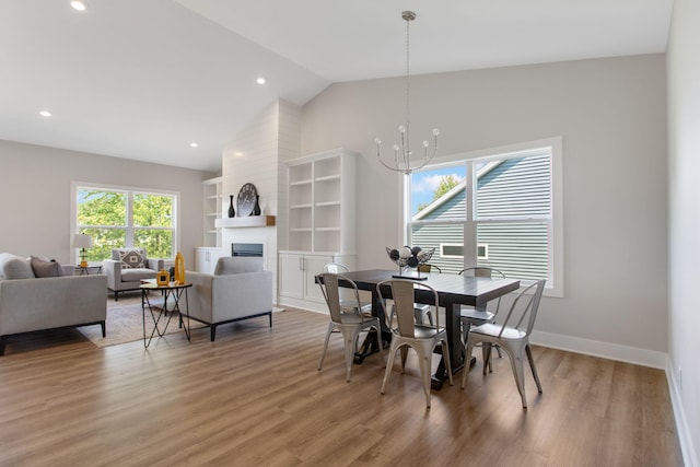 1519 Eagle Shore Ct, Hudsonville, MI 49426 - dining room featuring vaulted ceiling, a chandelier, a large fireplace, light wood finished floors, and recessed lighting